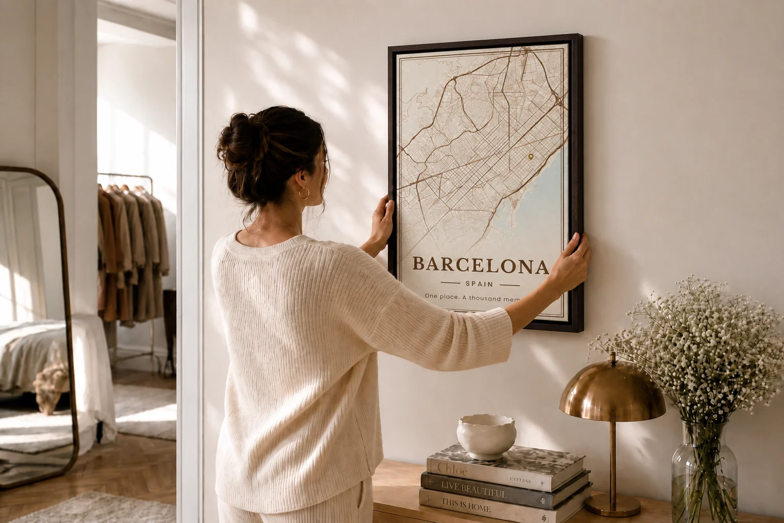 Une femme accroche au mur sa carte de Barcelone encadrée, dans la lumière du matin.