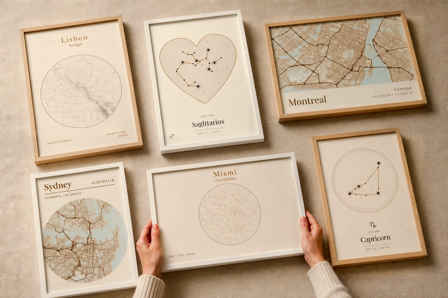 Six œuvres Emoria encadrées, posées à plat sur du lin : cartes de villes, ciels et constellations.